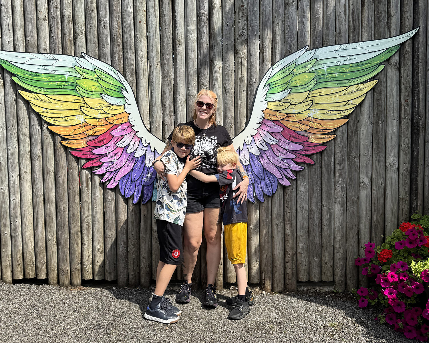 Gem and her boys cuddle in front of rainbow wings